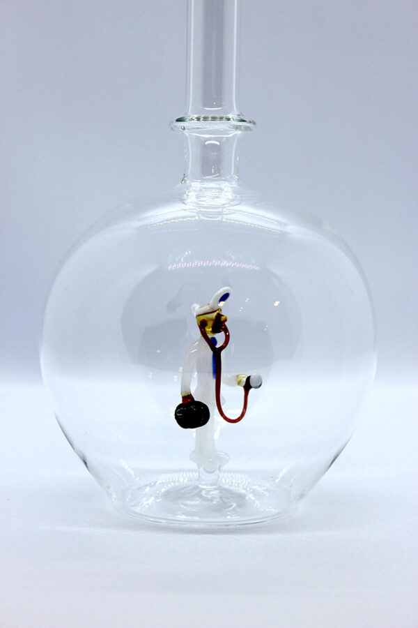 Eine leere bauchige Flasche aus Glas mit einem aus Glas geblasenen Arzt im Inneren.