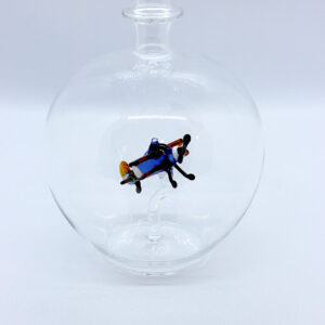 Eine leere bauchige Flasche aus Glas mit einem aus Glas geblasenen Doppeldecker im Inneren.