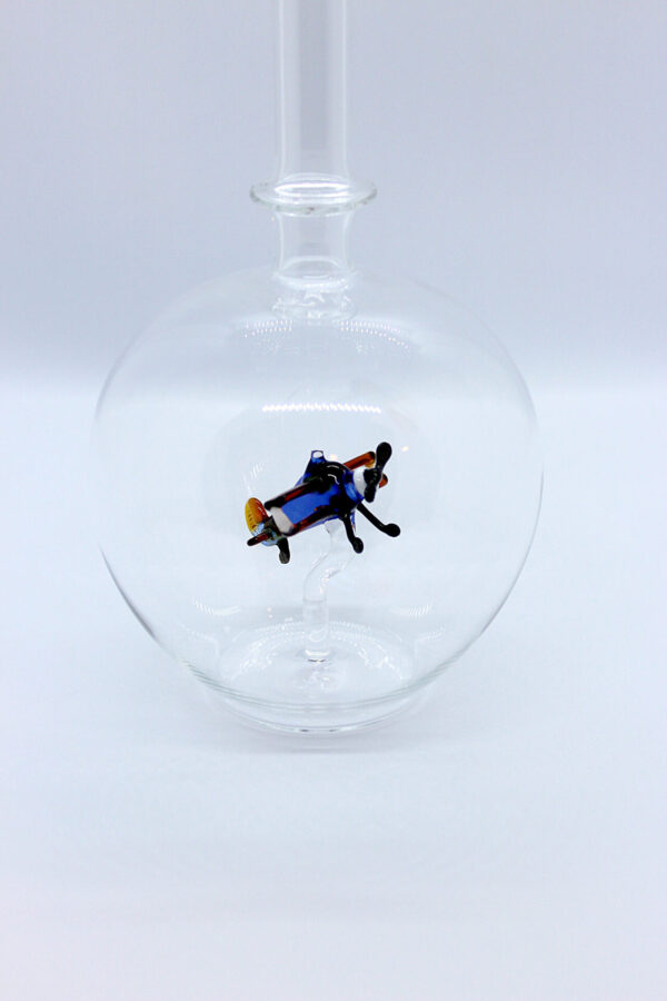 Eine leere bauchige Flasche aus Glas mit einem aus Glas geblasenen Doppeldecker im Inneren.