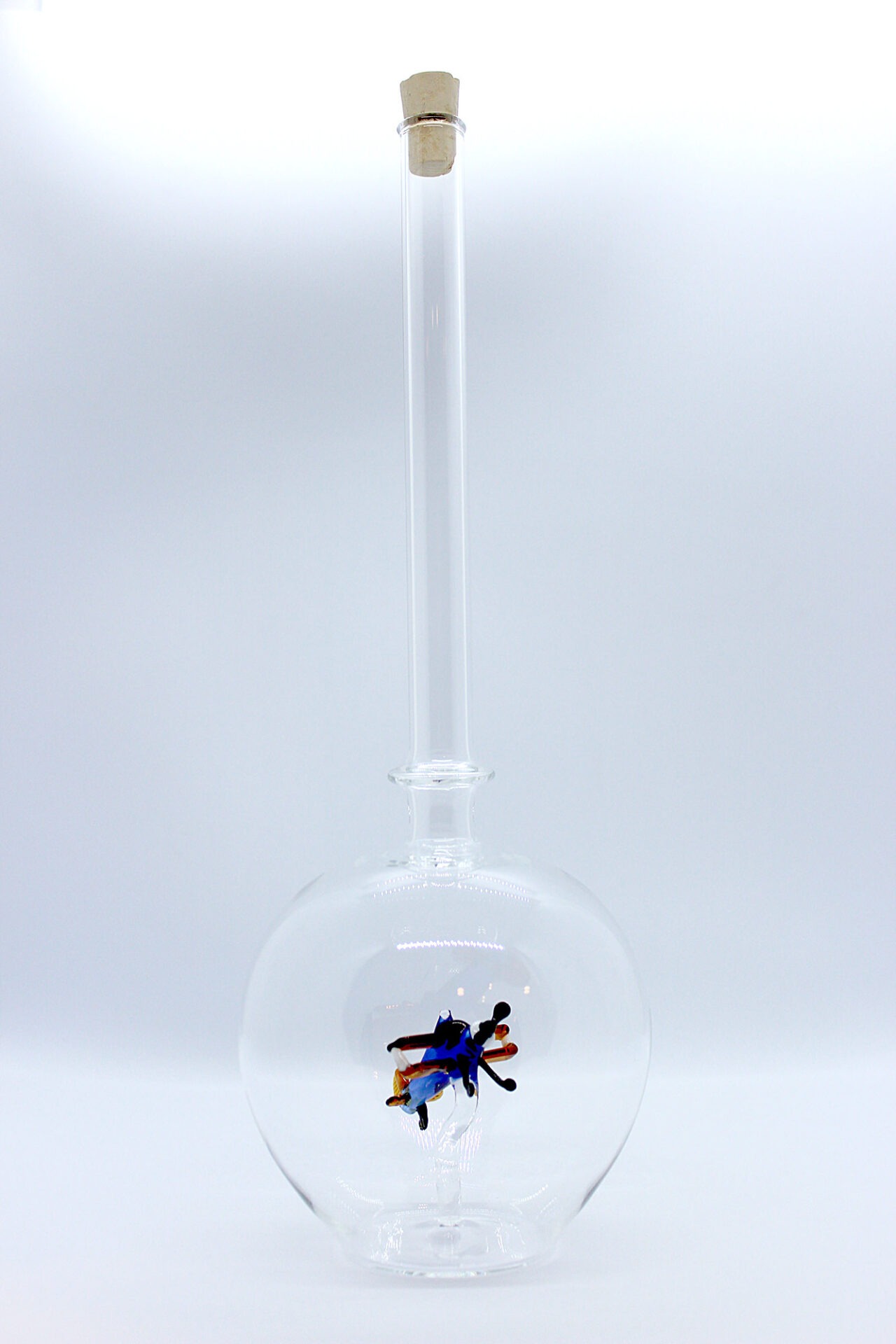 Eine leere bauchige Flasche aus Glas mit einem aus Glas geblasenen Doppeldecker im Inneren.