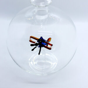 Eine leere bauchige Flasche aus Glas mit einem aus Glas geblasenen Doppeldecker im Inneren.