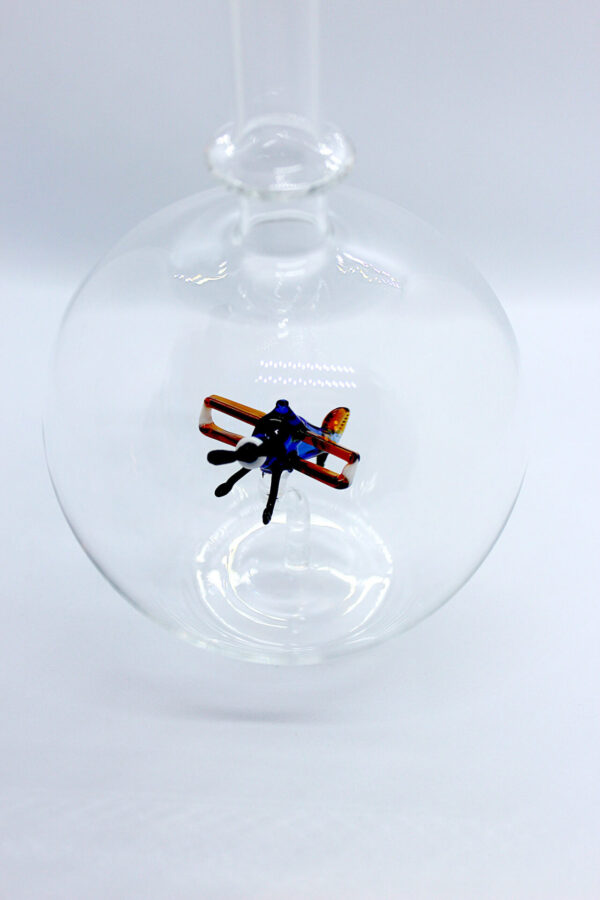 Eine leere bauchige Flasche aus Glas mit einem aus Glas geblasenen Doppeldecker im Inneren.