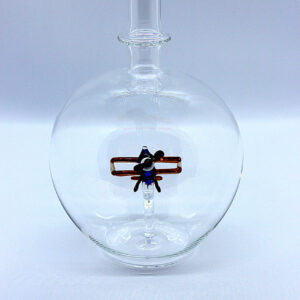 Eine leere bauchige Flasche aus Glas mit einem aus Glas geblasenen Doppeldecker im Inneren.