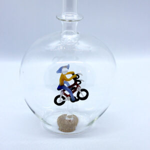 Eine leere bauchige Flasche aus Glas mit einem aus Glas geblasenen Radfahrer im Inneren.