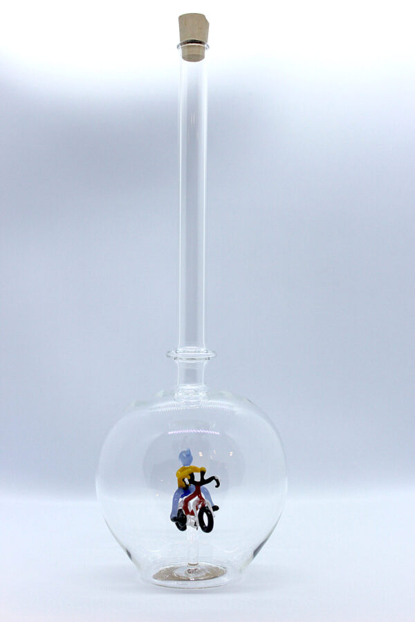 Eine leere bauchige Flasche aus Glas mit einem aus Glas geblasenen Radfahrer im Inneren.