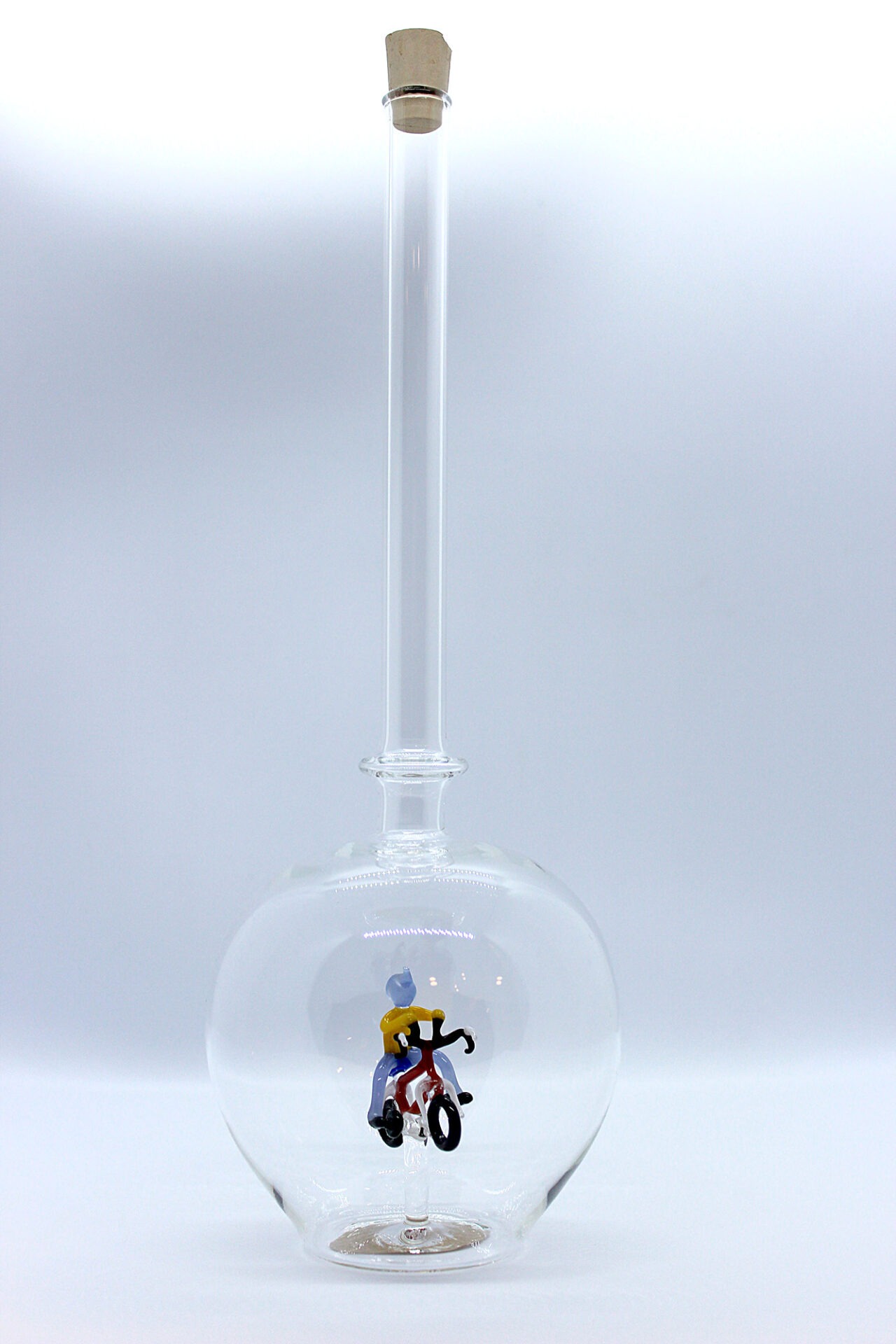 Eine leere bauchige Flasche aus Glas mit einem aus Glas geblasenen Radfahrer im Inneren.