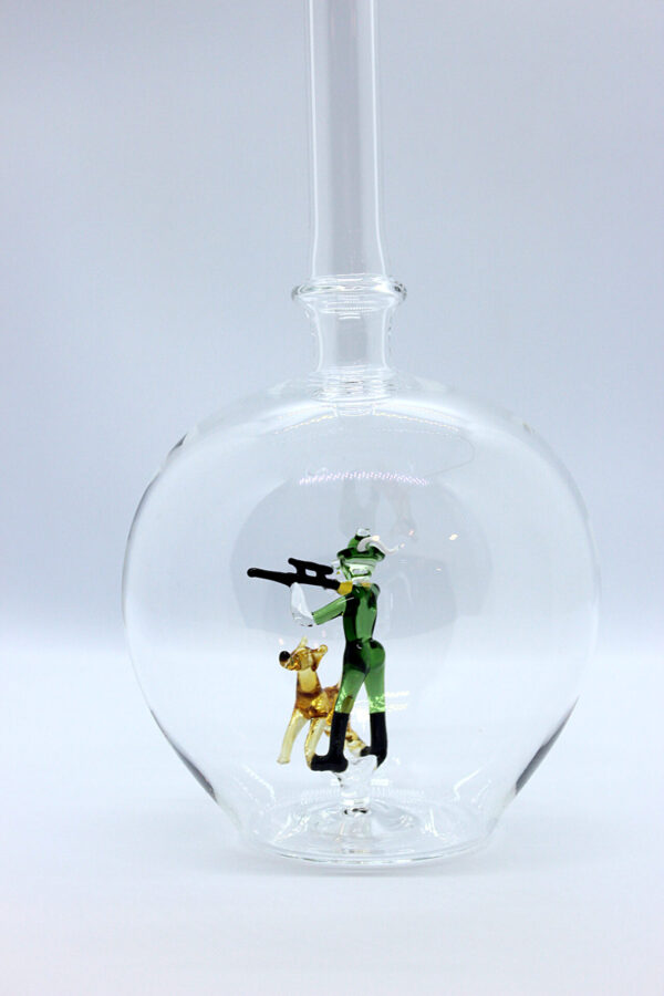 Eine leere bauchige Flasche aus Glas mit einem aus Glas geblasenen Jäger mit Hund im Inneren.