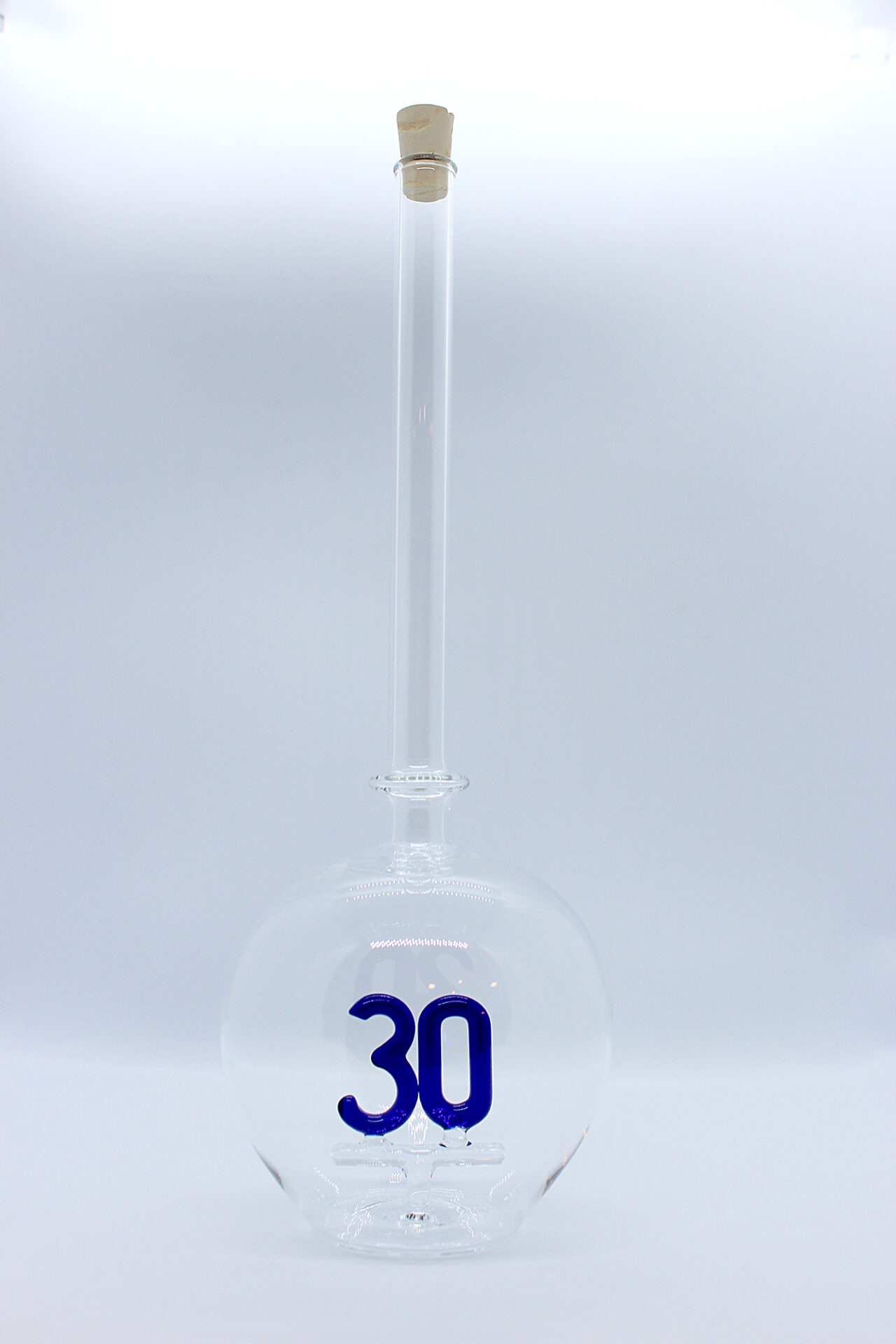 Eine leere bauchige Flasche aus Glas mit einer aus Glas geblasenen Zahl 30 im Inneren.