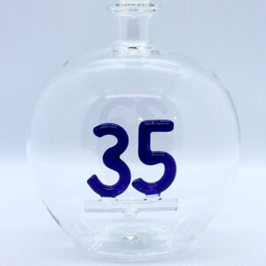 Eine leere bauchige Flasche aus Glas mit einer aus Glas geblasenen Zahl 35 im Inneren.
