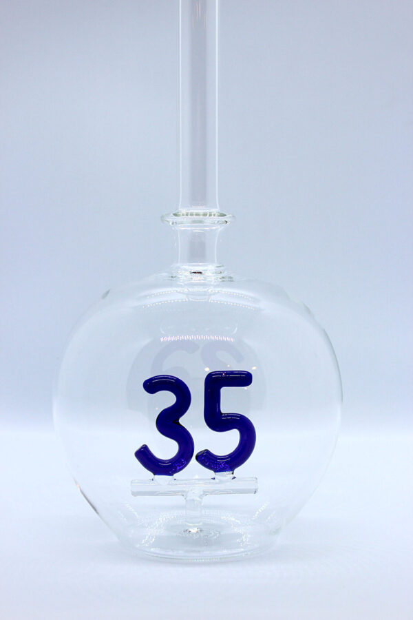 Eine leere bauchige Flasche aus Glas mit einer aus Glas geblasenen Zahl 35 im Inneren.