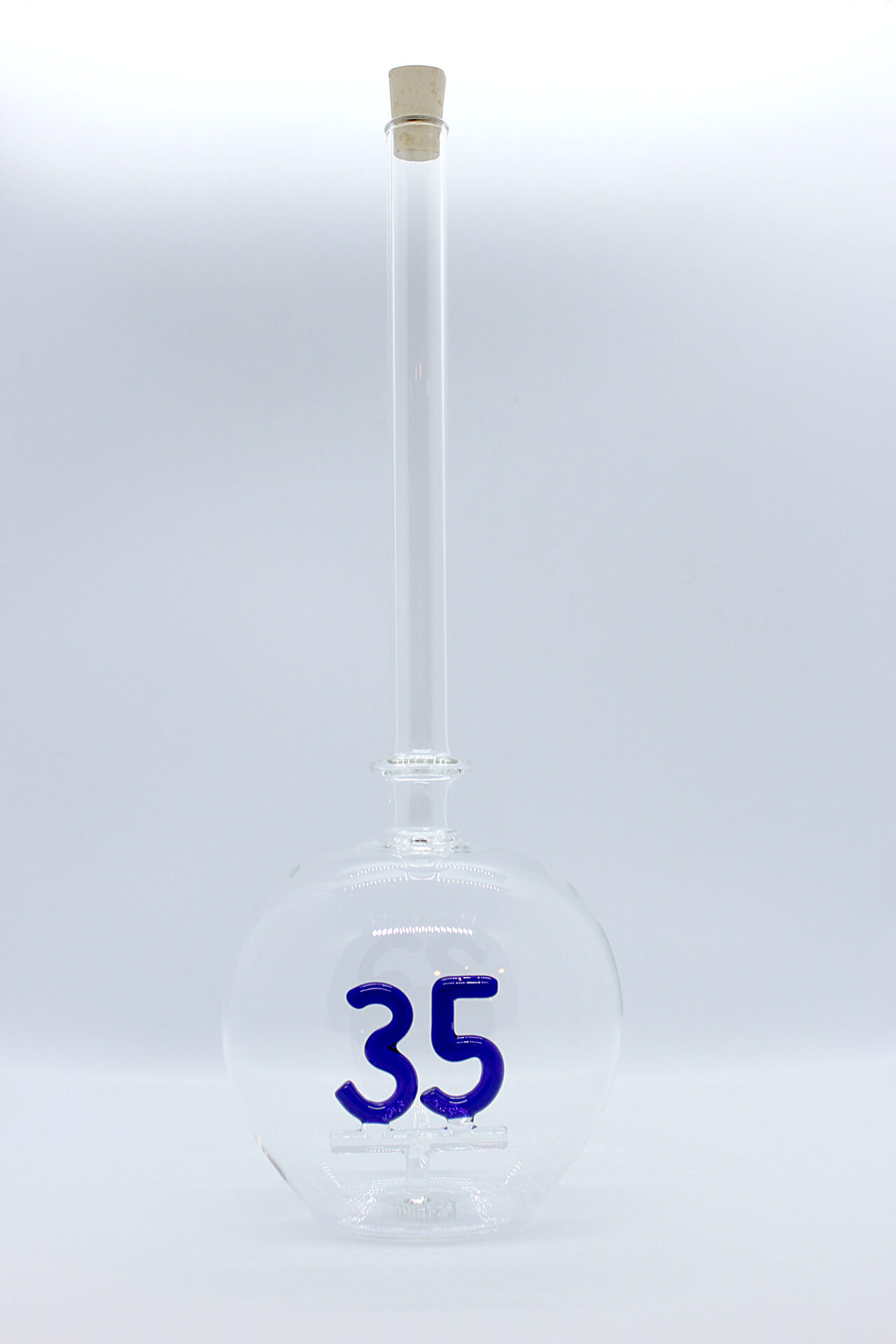 Eine leere bauchige Flasche aus Glas mit einer aus Glas geblasenen Zahl 35 im Inneren.