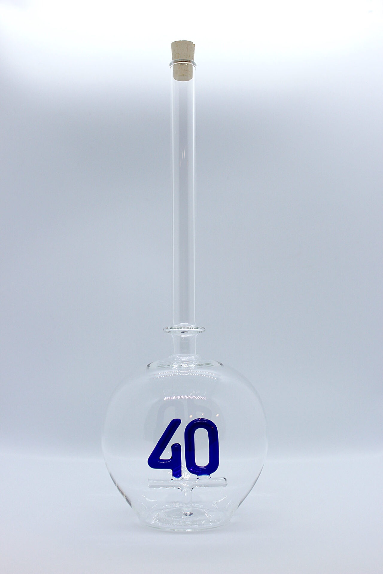 Eine leere bauchige Flasche aus Glas mit einer aus Glas geblasenen Zahl 40 im Inneren.