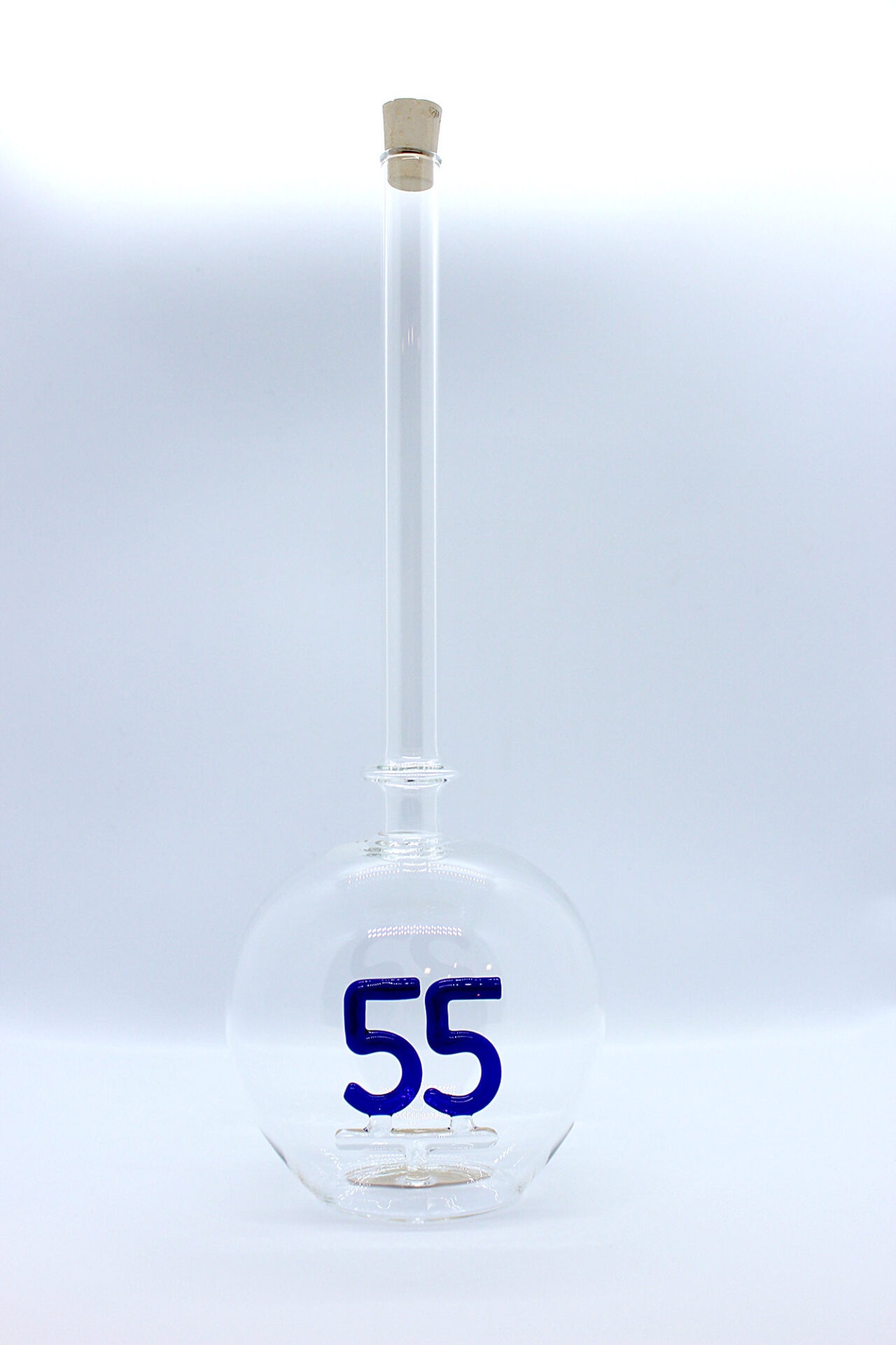 Eine leere bauchige Flasche aus Glas mit einer aus Glas geblasenen Zahl 55 im Inneren.