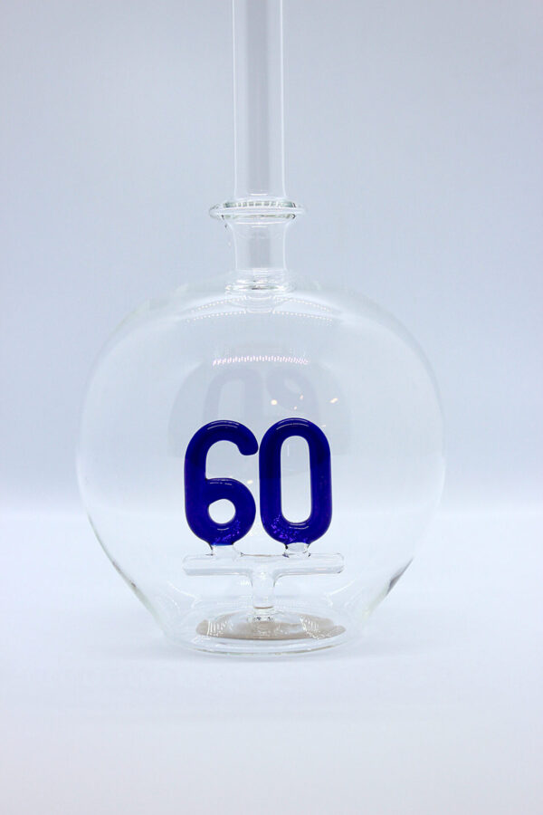 Eine leere bauchige Flasche aus Glas mit einer aus Glas geblasenen Zahl 60 im Inneren.
