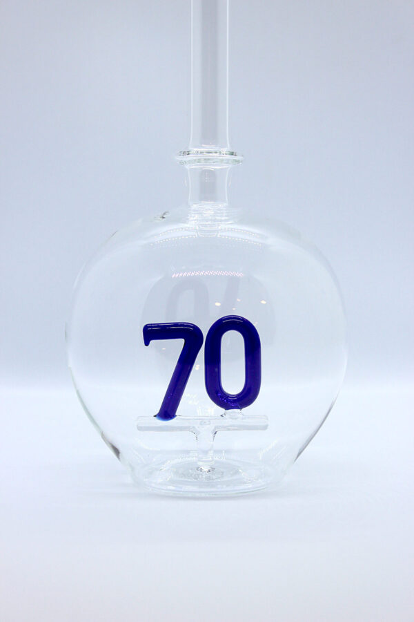 Eine leere bauchige Flasche aus Glas mit einer aus Glas geblasenen Zahl 70 im Inneren.