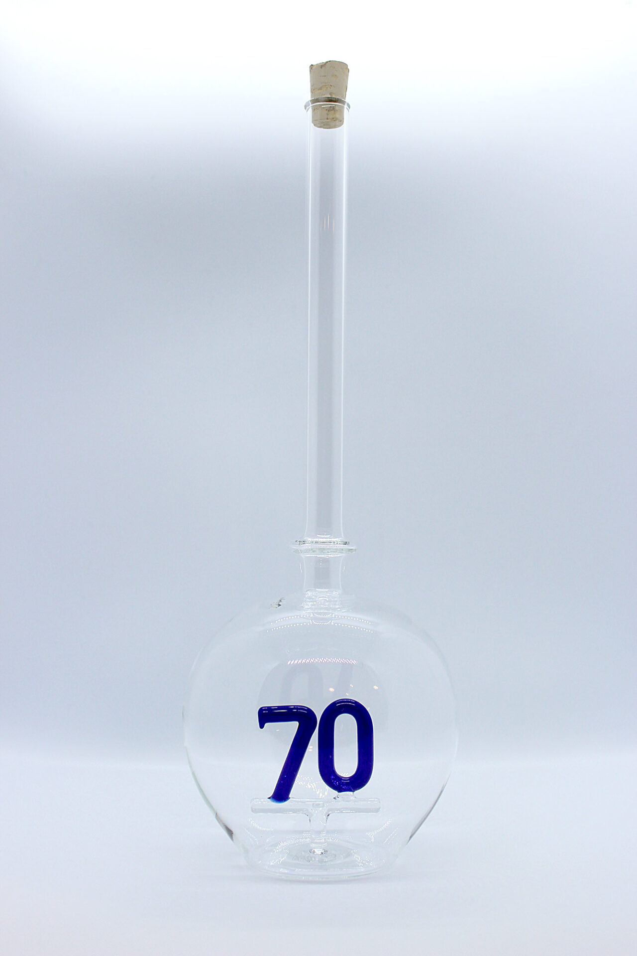 Eine leere bauchige Flasche aus Glas mit einer aus Glas geblasenen Zahl 70 im Inneren.