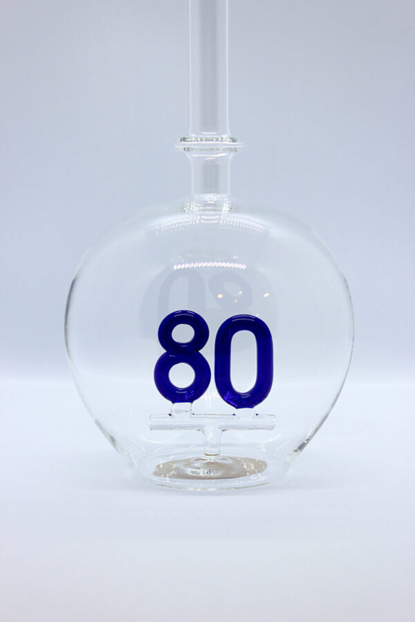 Eine leere bauchige Flasche aus Glas mit einer aus Glas geblasenen Zahl 80 im Inneren.