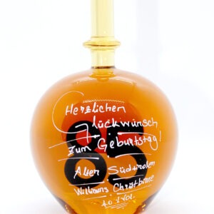 Eine mit Williams Christbirne befüllte bauchige Flasche aus Glas mit einer aus Glas geblasenen Zahl 85 im Inneren.