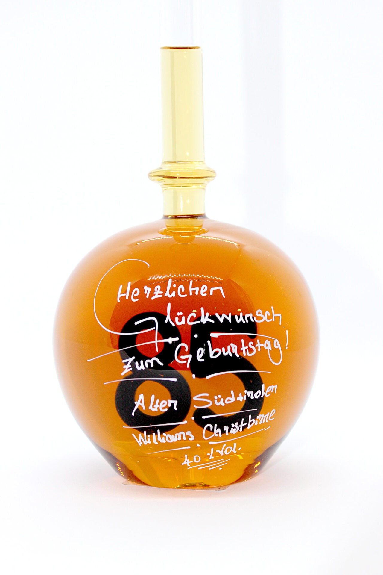 Eine mit Williams Christbirne befüllte bauchige Flasche aus Glas mit einer aus Glas geblasenen Zahl 85 im Inneren.