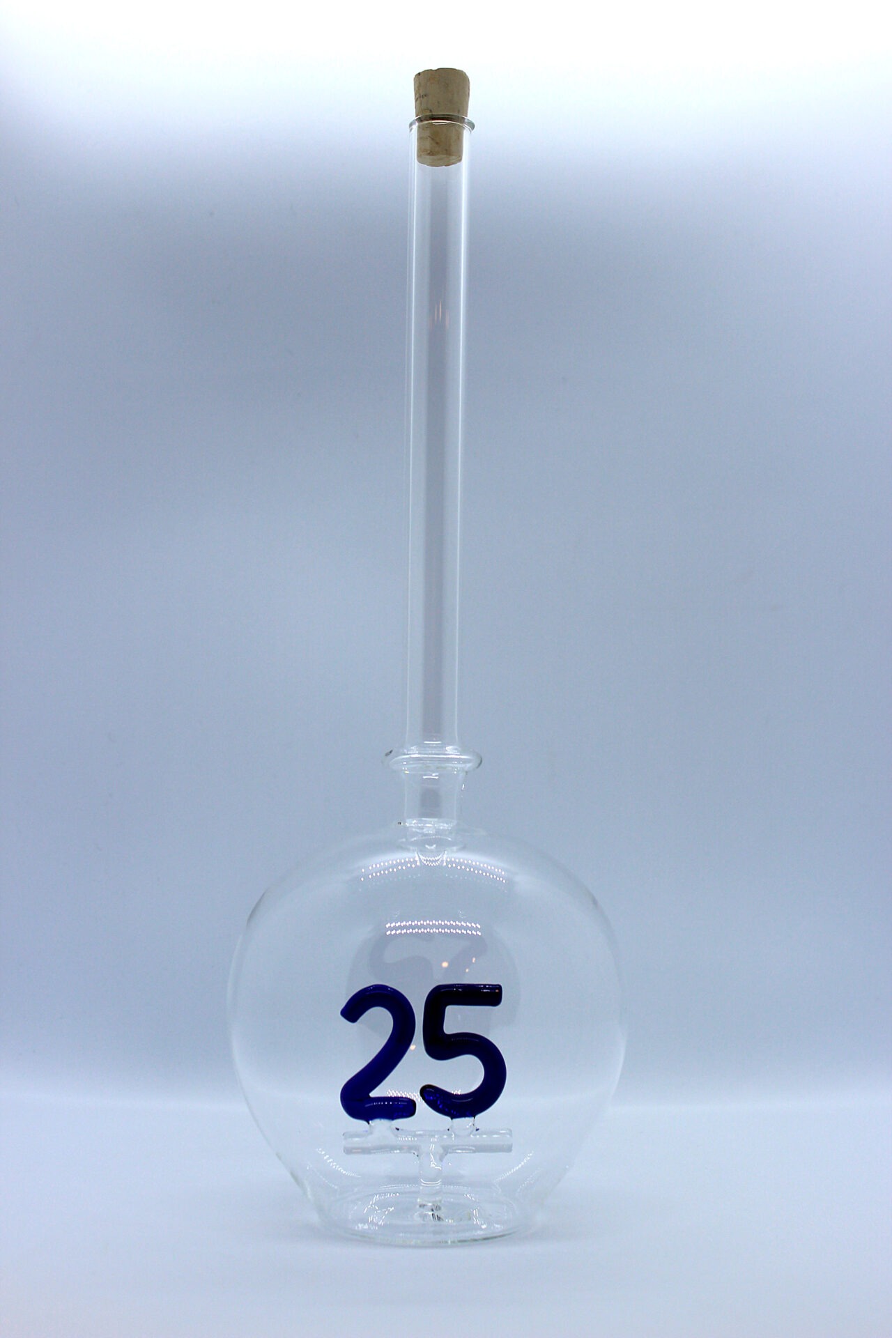 Eine leere bauchige Flasche aus Glas mit einer aus Glas geblasenen Zahl 25 im Inneren.