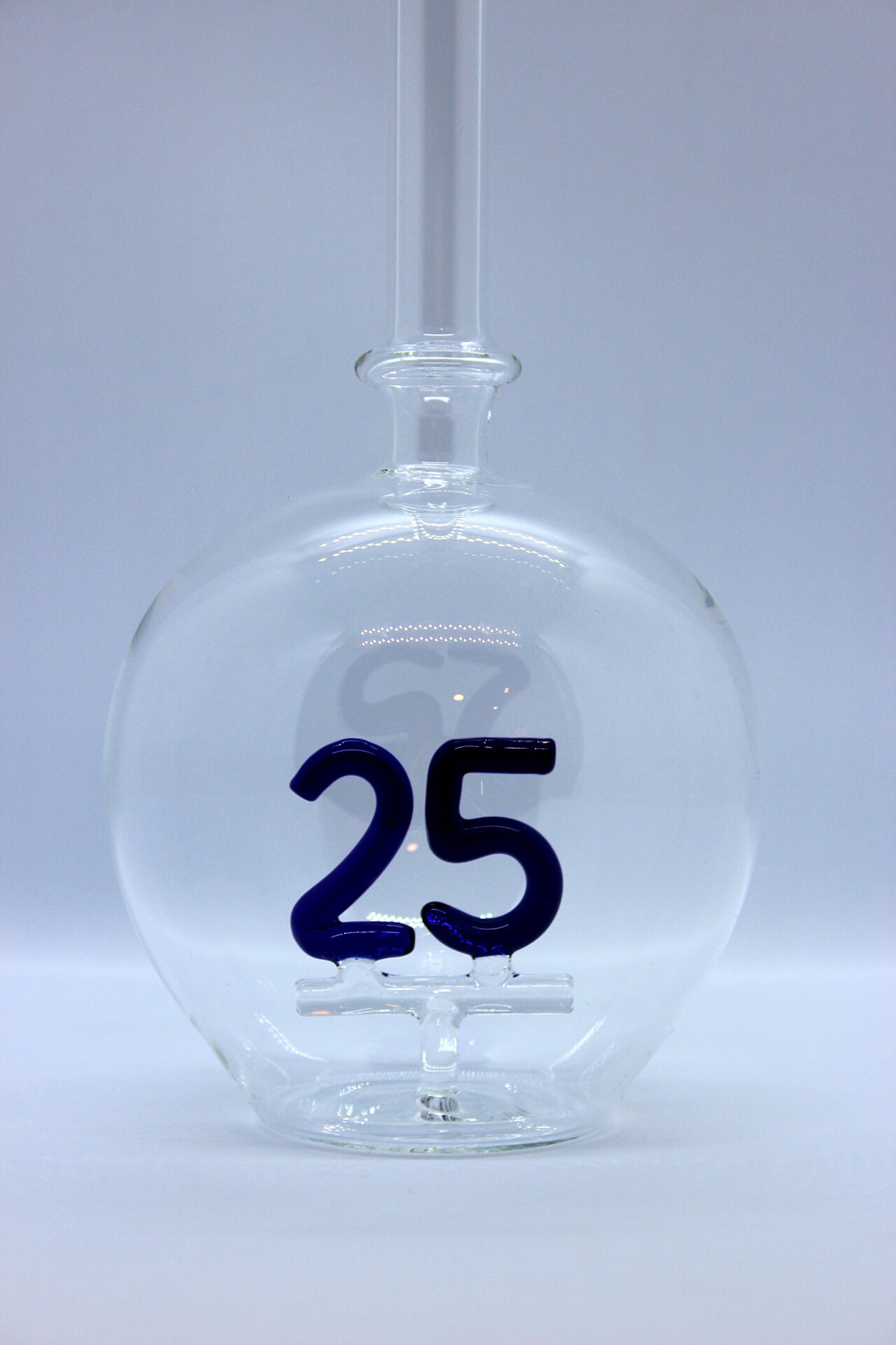 Eine leere bauchige Flasche aus Glas mit einer aus Glas geblasenen Zahl 25 im Inneren.