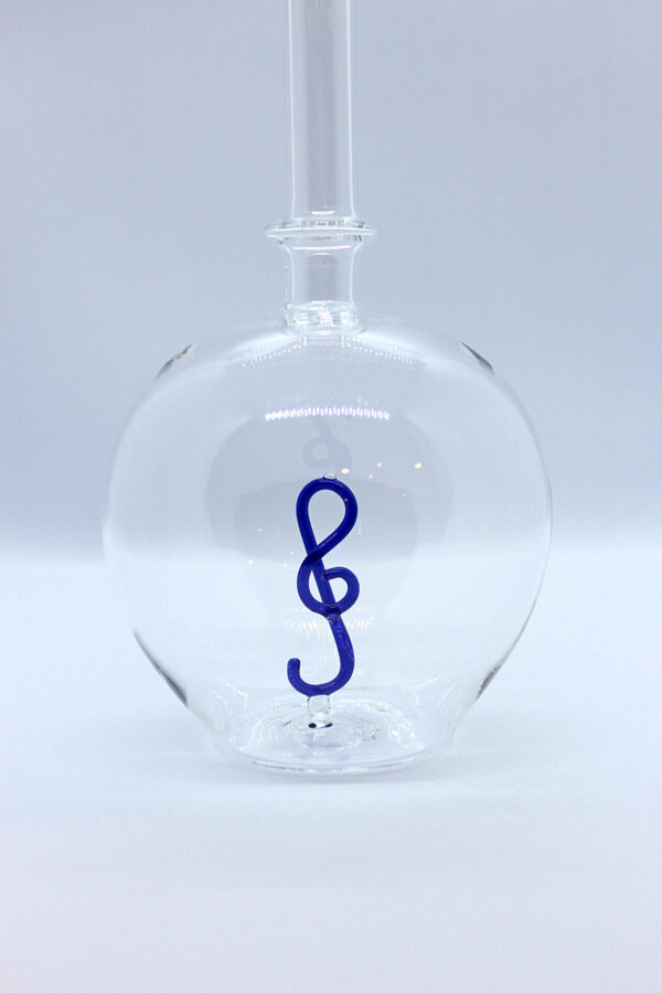Eine leere bauchige Flasche aus Glas mit einem aus Glas geblasenen Notenschlüssel im Inneren.