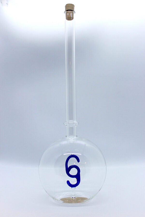 Eine leere bauchige Flasche aus Glas mit einem aus Glas geblasenen Paragraphen-Zeichen im Inneren.