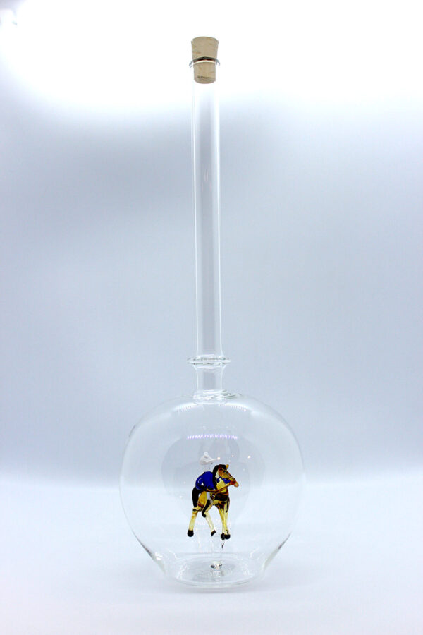 Eine leere bauchige Flasche aus Glas mit einem aus Glas geblasenen Reiter auf einem Pferd im Inneren.