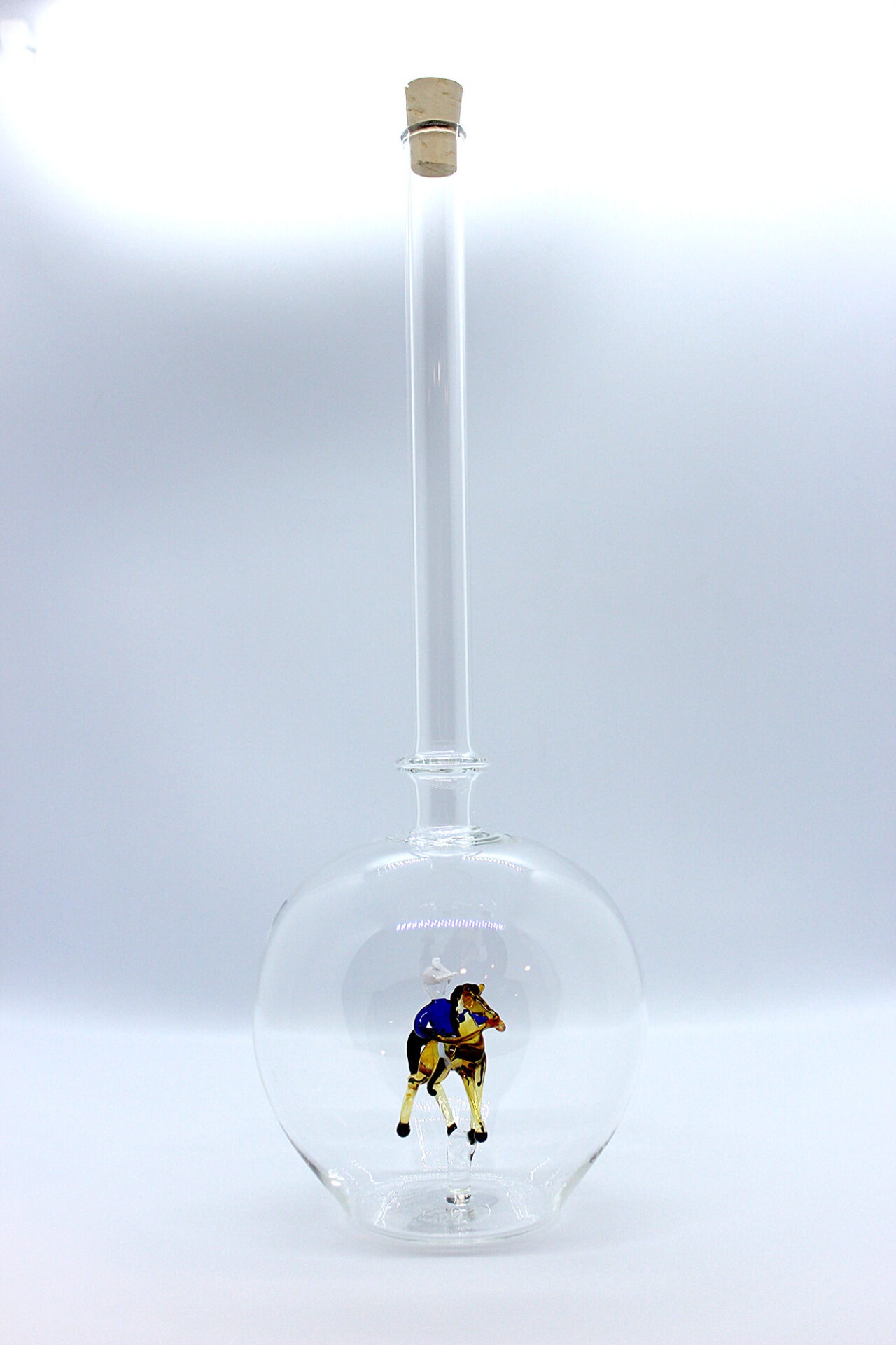 Eine leere bauchige Flasche aus Glas mit einem aus Glas geblasenen Reiter auf einem Pferd im Inneren.
