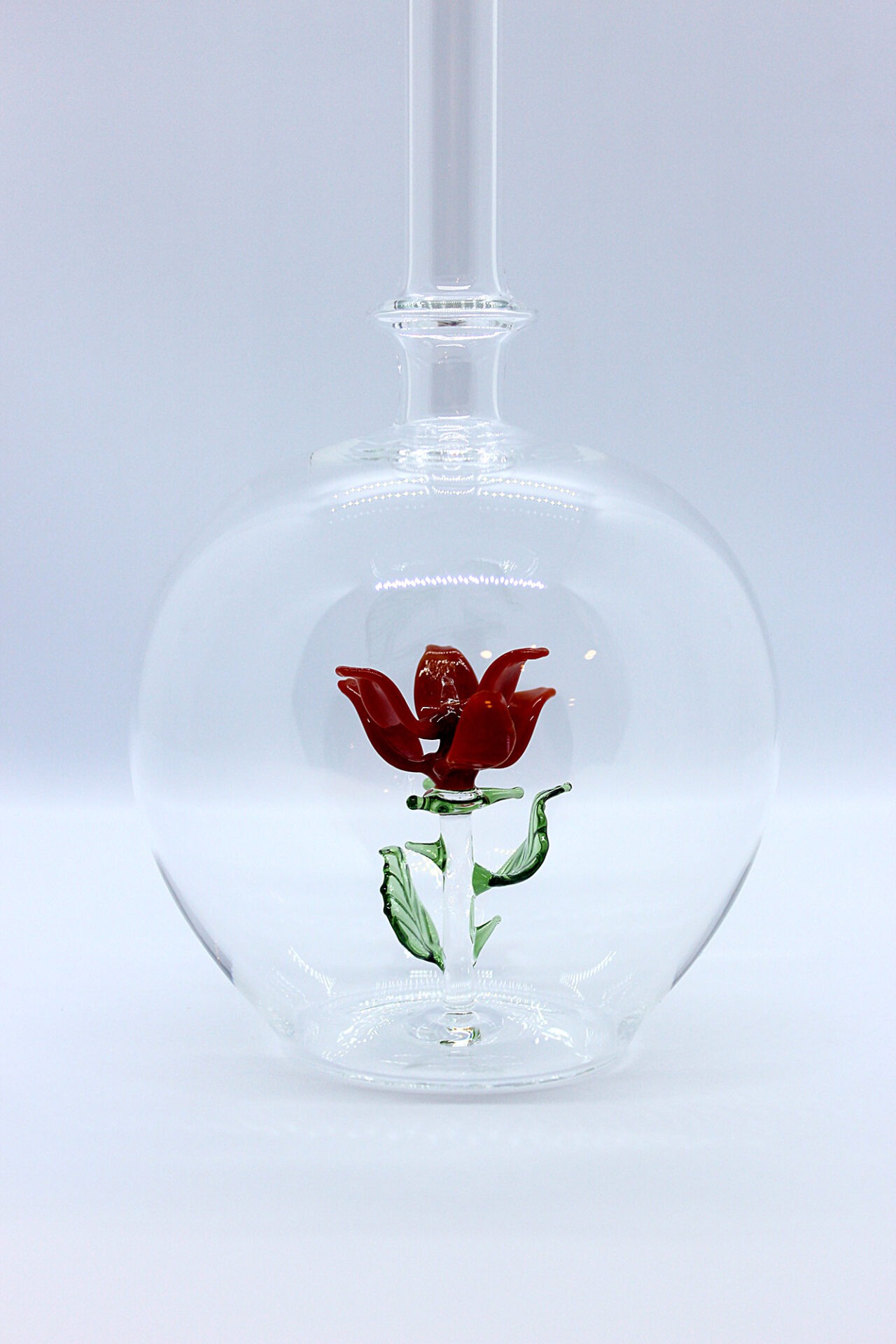 Eine leere bauchige Flasche aus Glas mit einer aus Glas geblasenen Rose im Inneren.