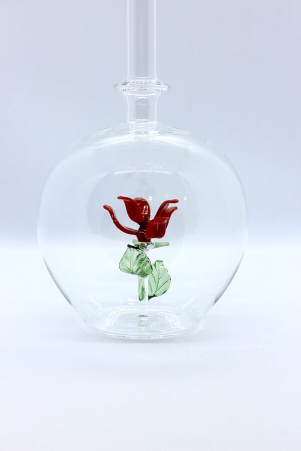 Eine leere bauchige Flasche aus Glas mit einer aus Glas geblasenen Rose im Inneren.