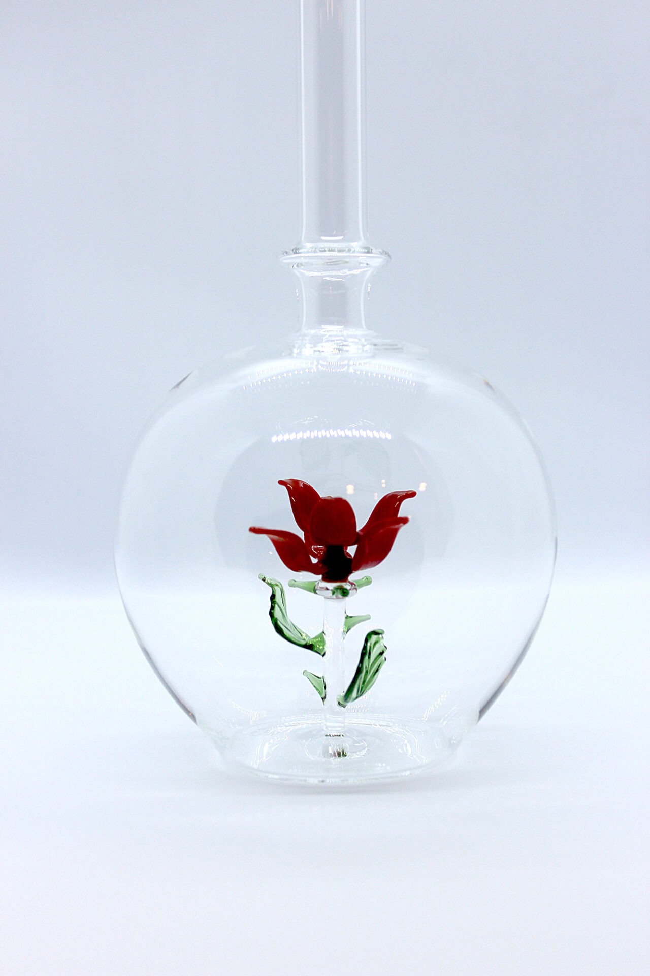 Eine leere bauchige Flasche aus Glas mit einer aus Glas geblasenen Rose im Inneren.