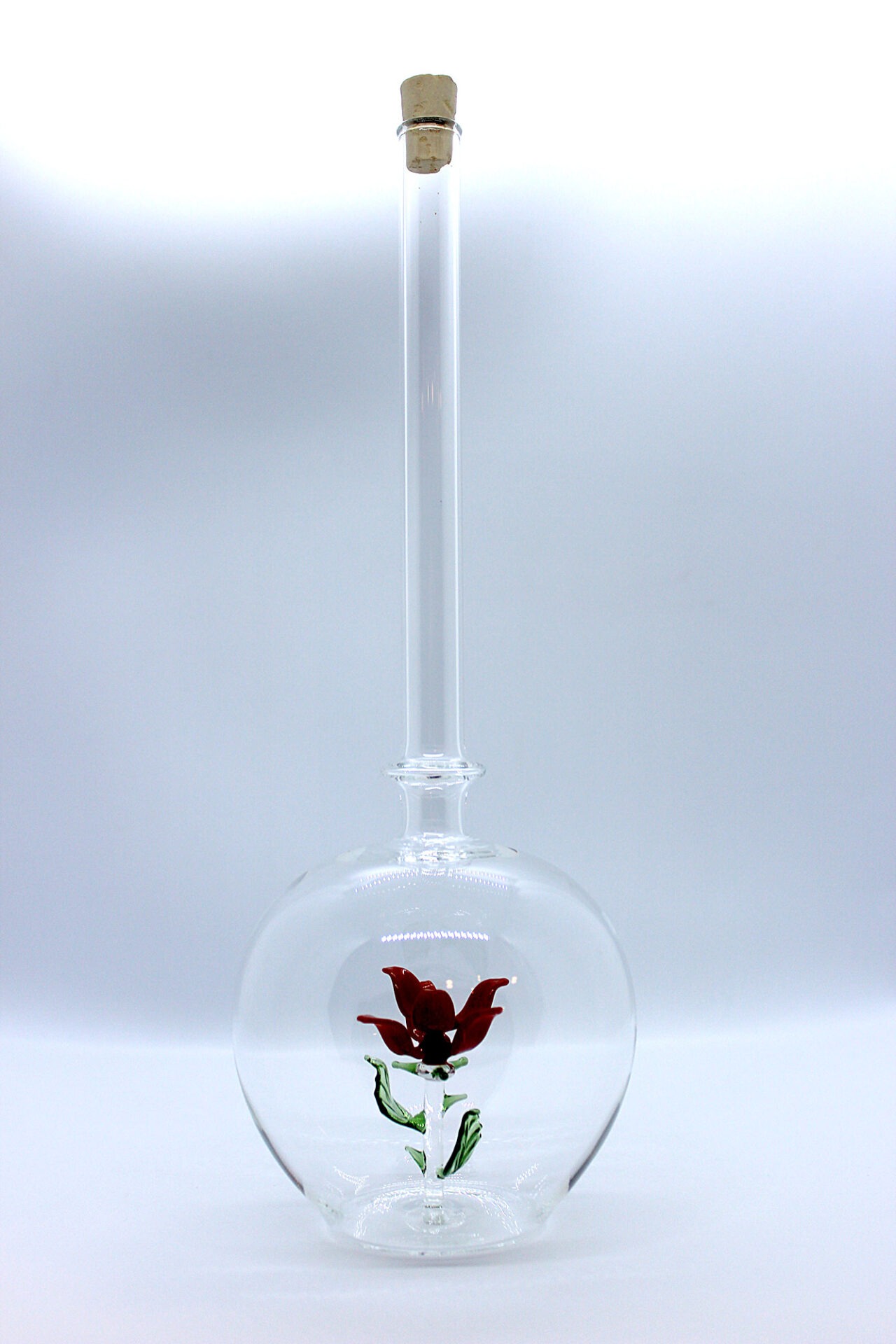 Eine leere bauchige Flasche aus Glas mit einer aus Glas geblasenen Rose im Inneren.
