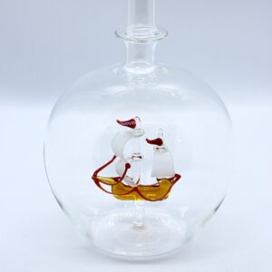 Eine leere bauchige Flasche aus Glas mit einem aus Glas geblasenen Segelschiff im Inneren.