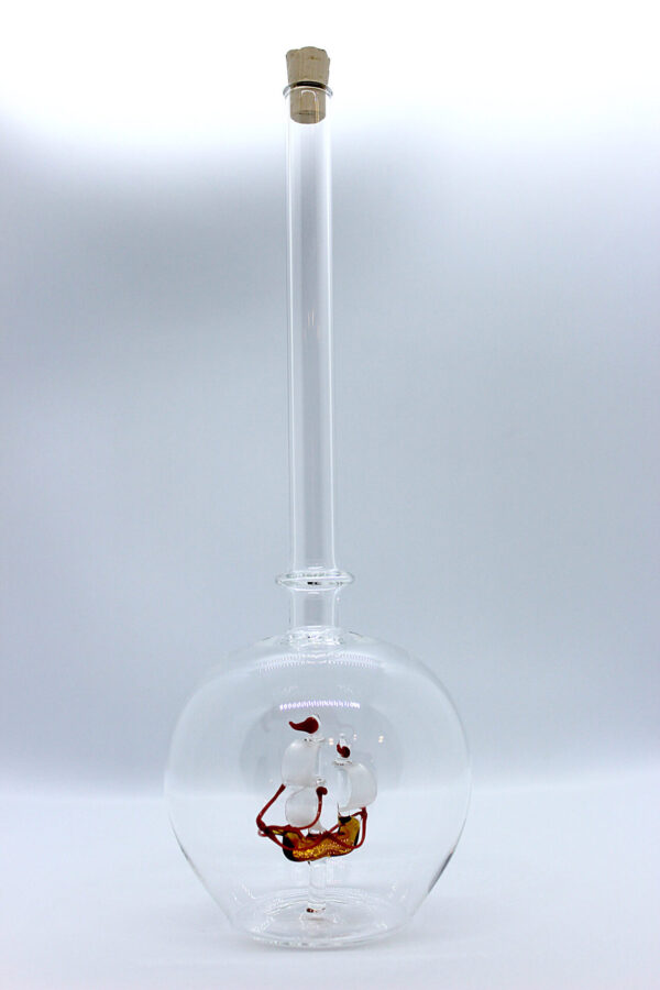 Eine leere bauchige Flasche aus Glas mit einem aus Glas geblasenen Segelschiff im Inneren.