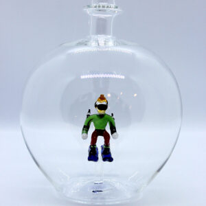 Eine leere bauchige Flasche aus Glas mit einem aus Glas geblasenen Skifahrer im Inneren.
