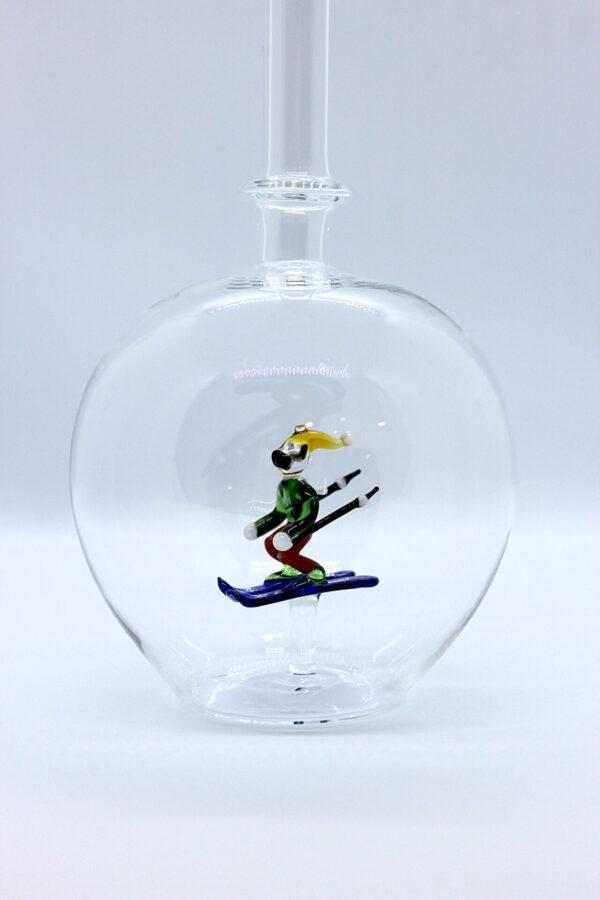 Eine leere bauchige Flasche aus Glas mit einem aus Glas geblasenen Skifahrer im Inneren.