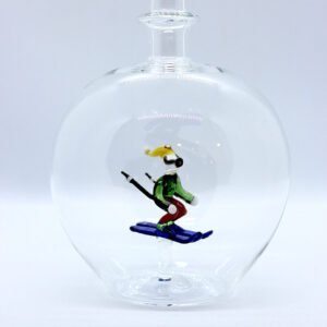 Motivflasche mit Skifahrer 500 ml Eine leere bauchige Flasche aus Glas mit einem aus Glas geblasenen Skifahrer im Inneren.