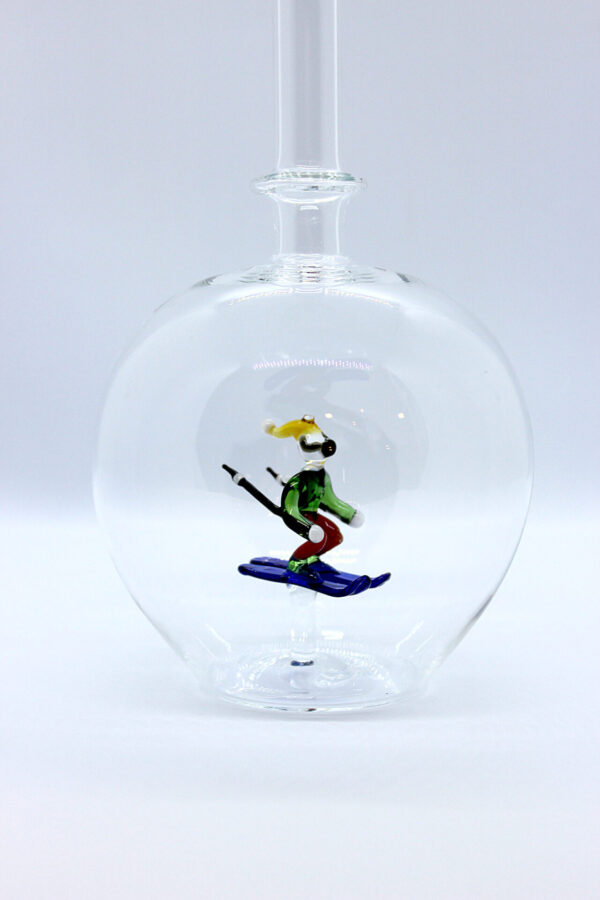 Eine leere bauchige Flasche aus Glas mit einem aus Glas geblasenen Skifahrer im Inneren.