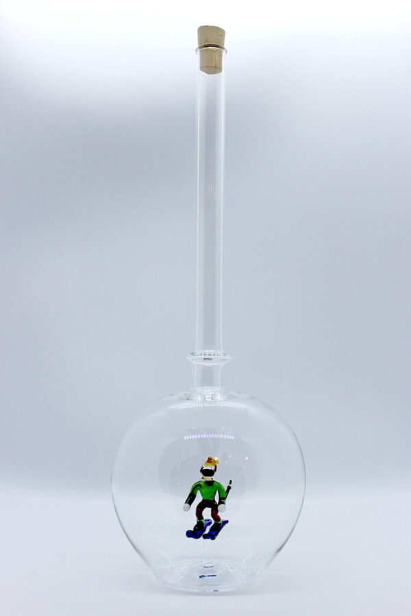 Eine leere bauchige Flasche aus Glas mit einem aus Glas geblasenen Skifahrer im Inneren.