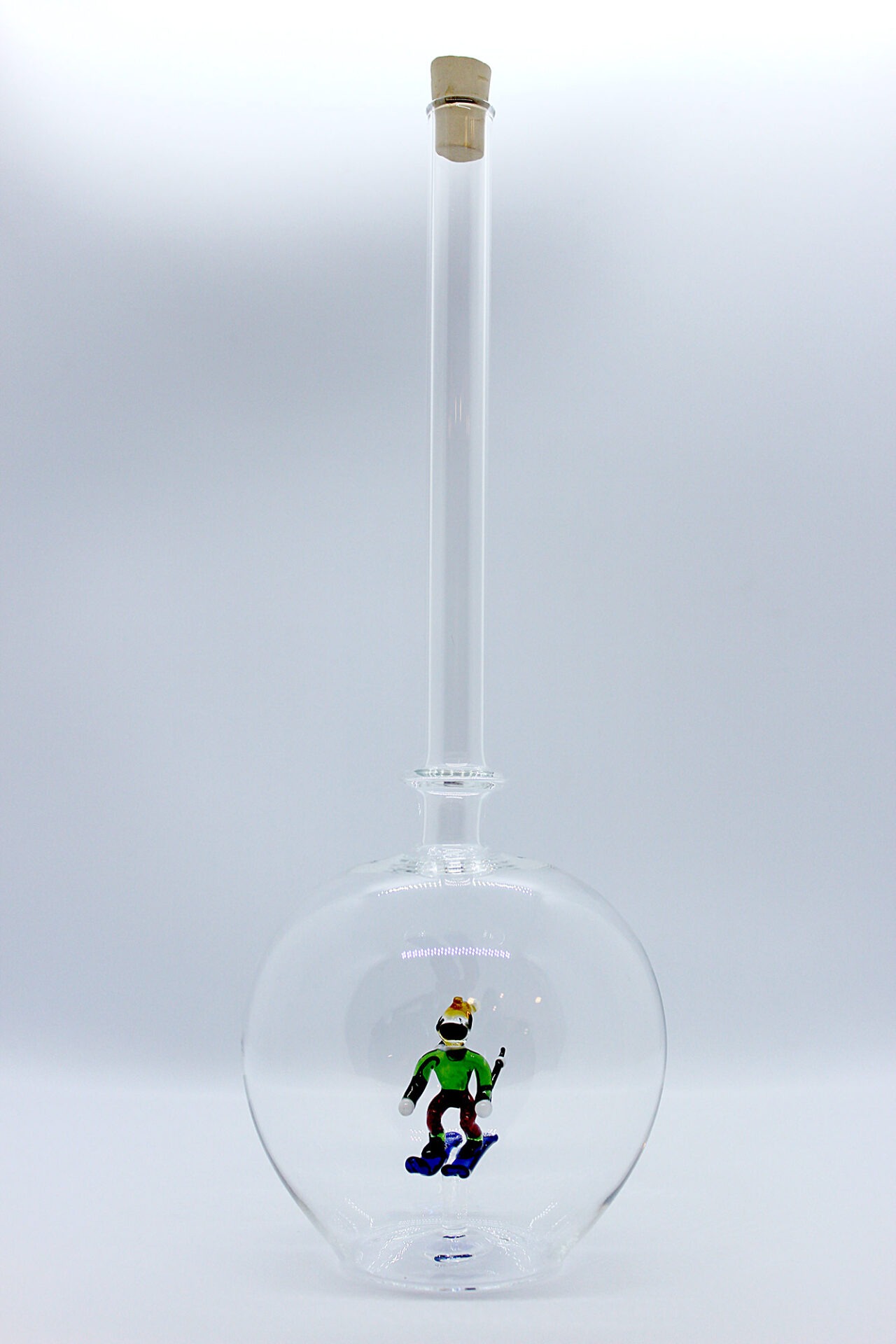 Eine leere bauchige Flasche aus Glas mit einem aus Glas geblasenen Skifahrer im Inneren.