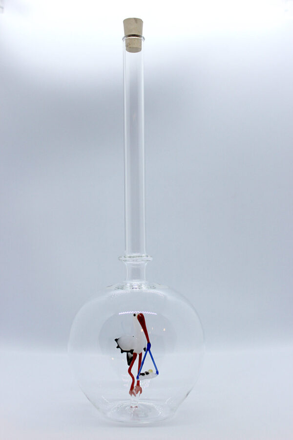 Eine leere bauchige Flasche aus Glas mit einem aus Glas geblasenen Storch mit Baby im Inneren.