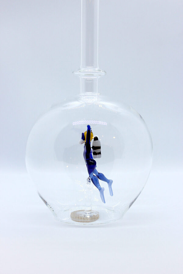 Eine leere bauchige Flasche aus Glas mit einem aus Glas geblasenen Taucher im Inneren.