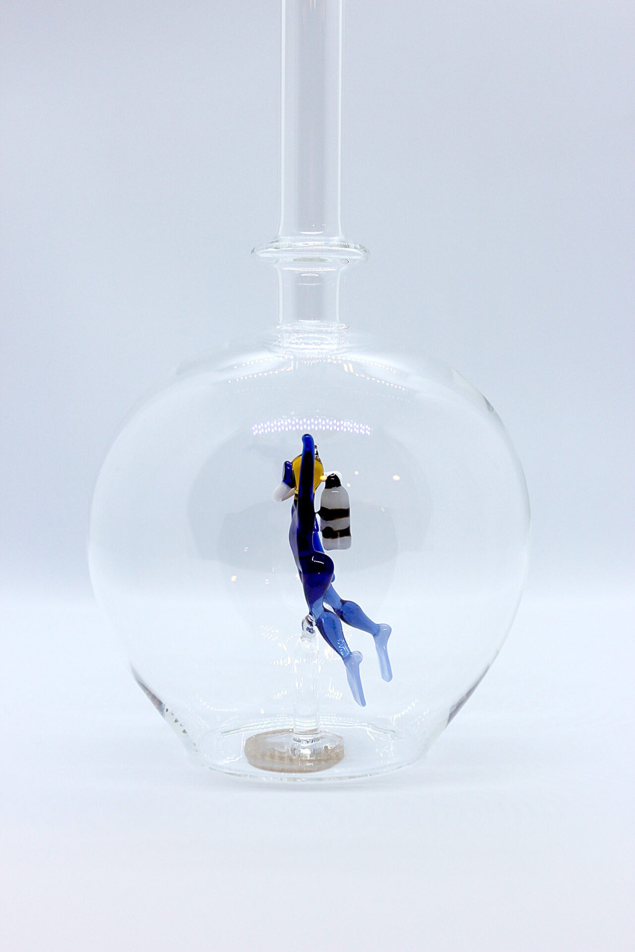 Eine leere bauchige Flasche aus Glas mit einem aus Glas geblasenen Taucher im Inneren.