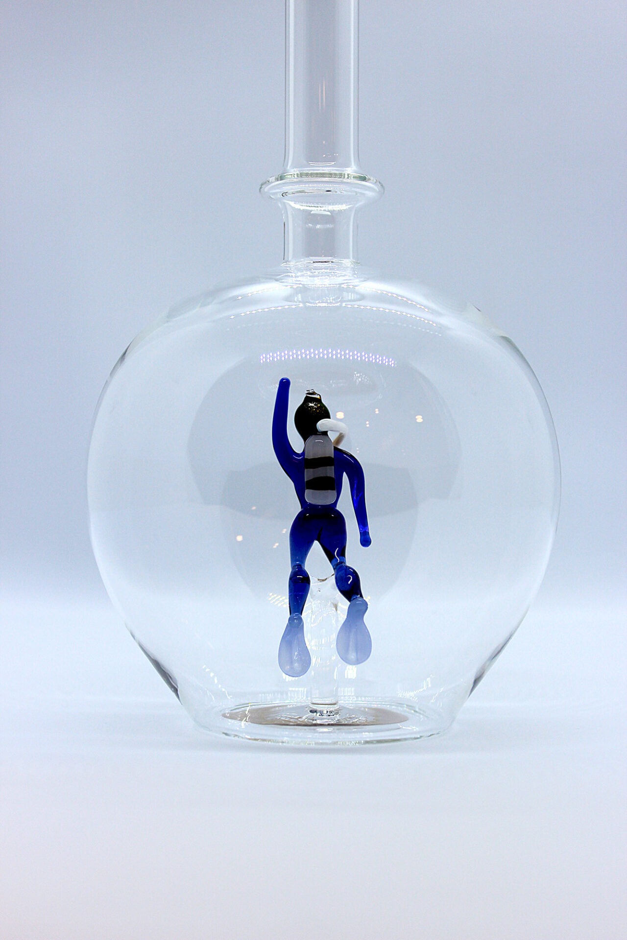 Eine leere bauchige Flasche aus Glas mit einem aus Glas geblasenen Taucher im Inneren.