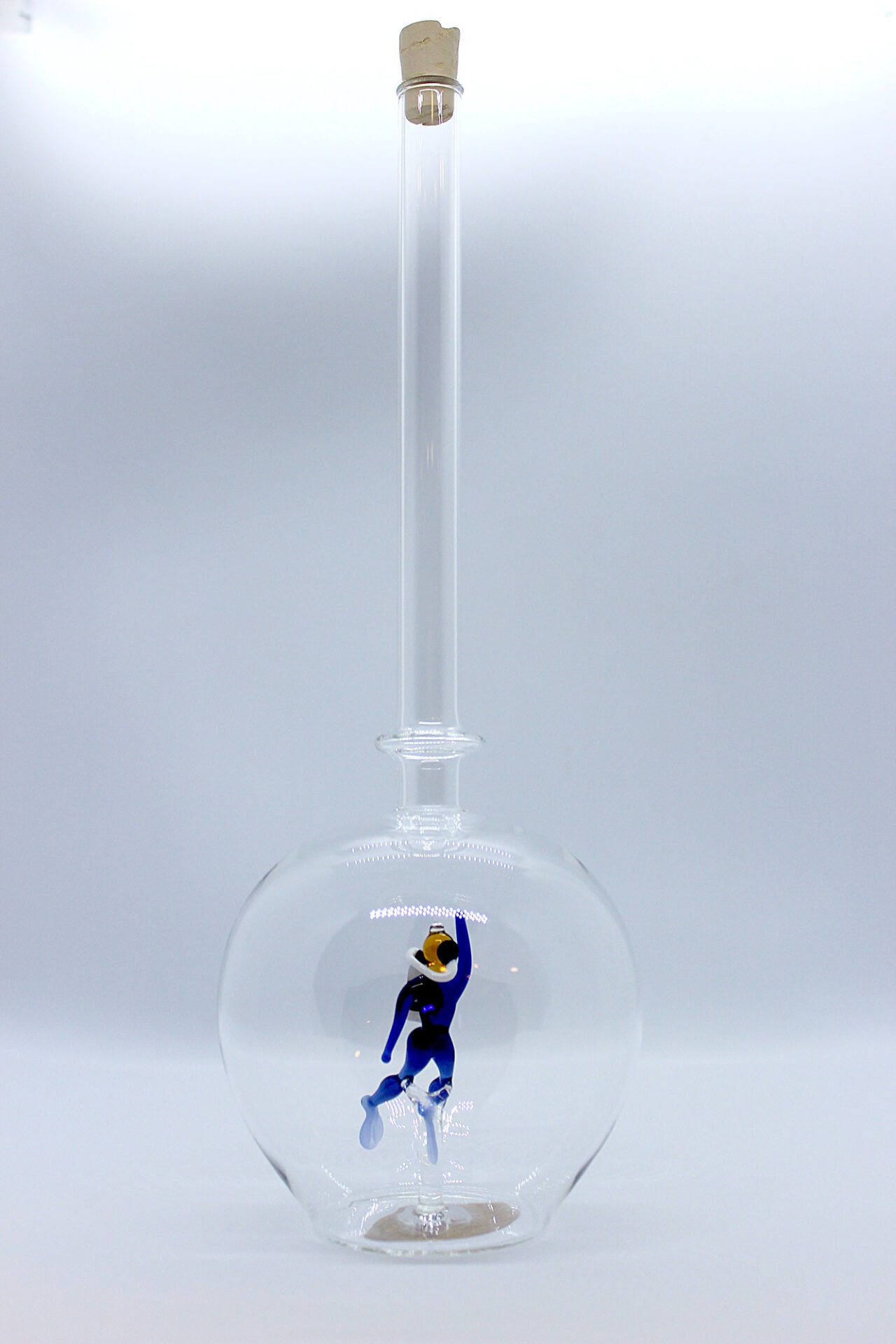 Eine leere bauchige Flasche aus Glas mit einem aus Glas geblasenen Taucher im Inneren.