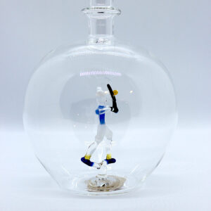 Motivflasche mit Tennisspieler 500 ml Eine leere bauchige Flasche aus Glas mit einem aus Glas geblasenen Tennisspieler im Inneren.