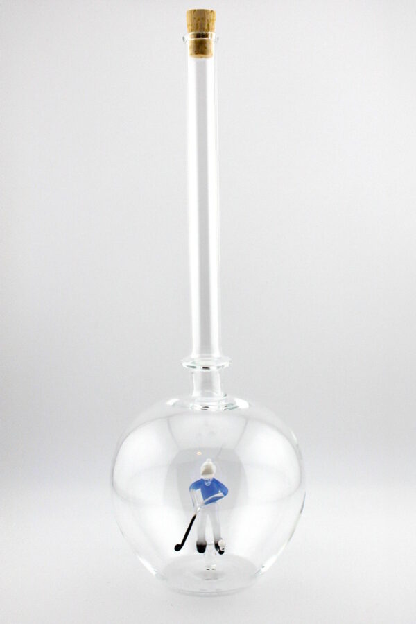 Eine leere bauchige Flasche aus Glas mit einem aus Glas geblasenen Golfspieler im Inneren.
