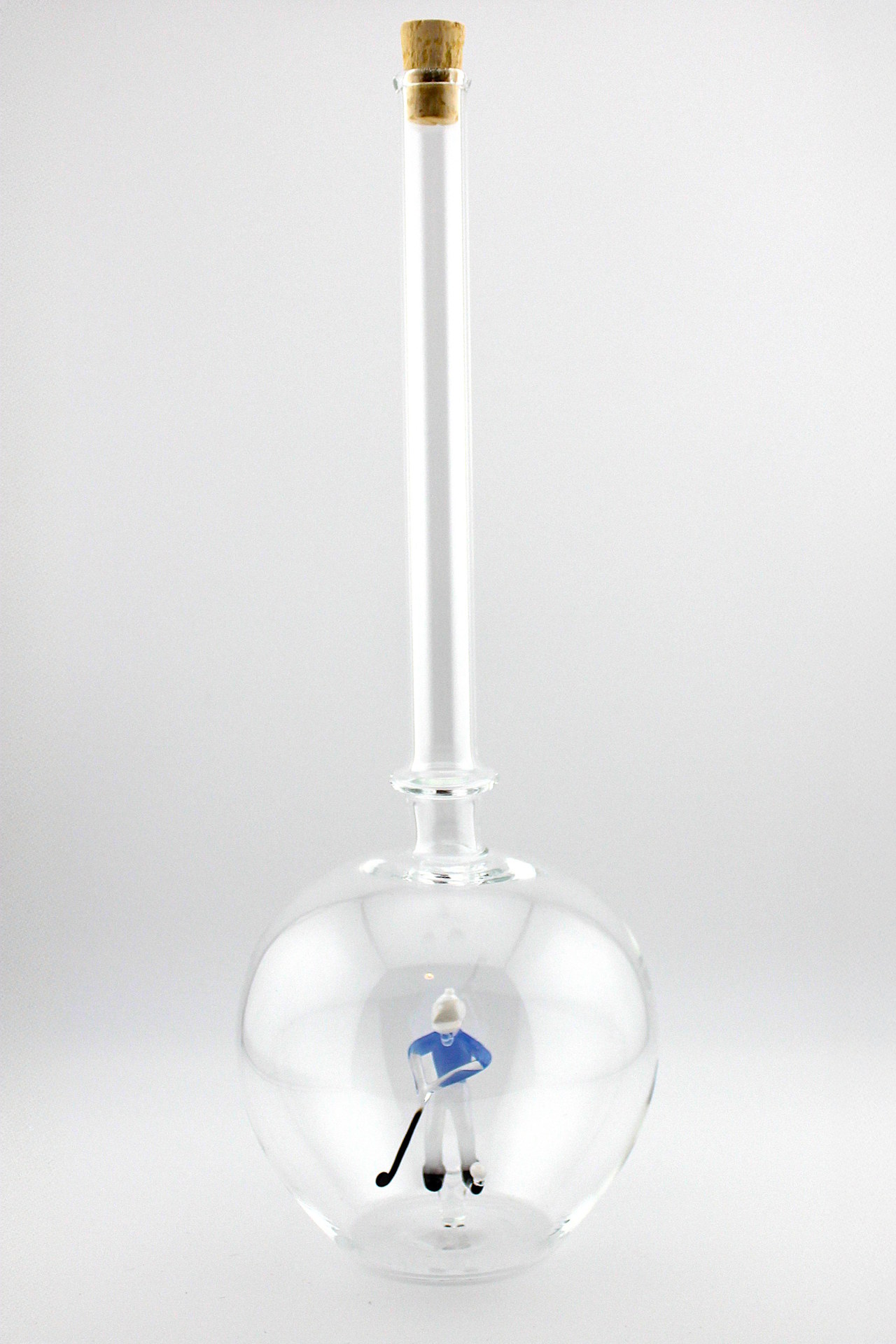 Eine leere bauchige Flasche aus Glas mit einem aus Glas geblasenen Golfspieler im Inneren.