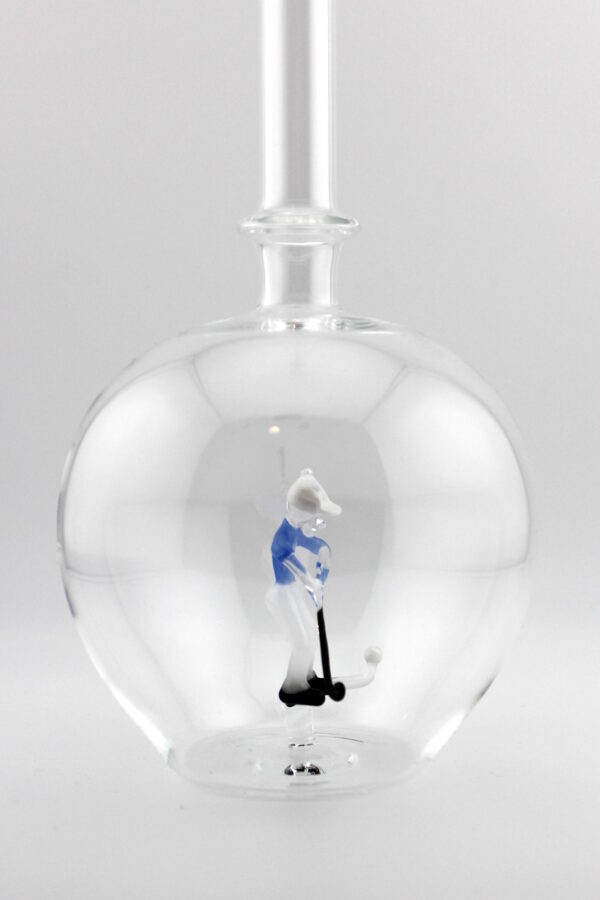 Eine leere bauchige Flasche aus Glas mit einem aus Glas geblasenen Golfspieler im Inneren.